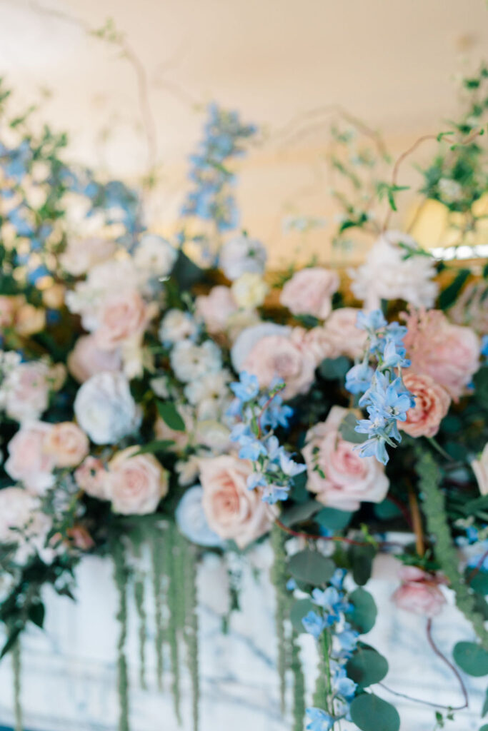 Shining Tides Weddings | Caprio Captured Photography Light and Airy Wedding Photography | Soft pastel flowers, including pink roses and blue blossoms, interspersed with lush greenery. The bouquet creates an elegant and serene atmosphere.